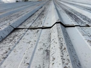 A standard metal roof panel seam pulled apart, exposing gap. 