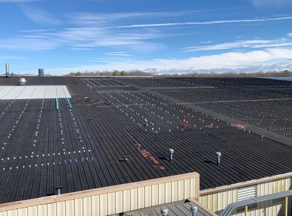 Plastics Manufacturer Roof in progress showing a portion of inevitably 15,000 brackets for solar panels.